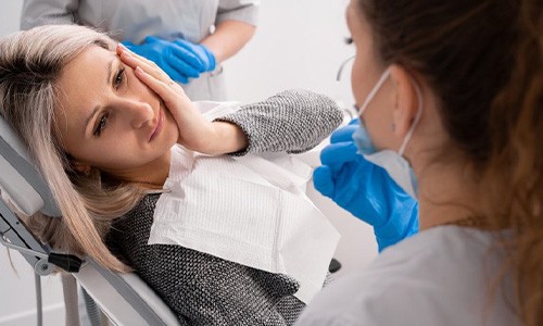 Lady with oral pain looks to dentist