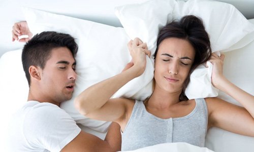 Man snoring while his wife covers her ears