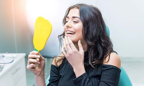 Woman looking at her teeth in a dental mirror