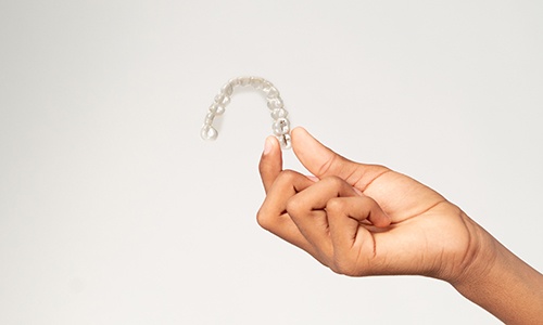 Smiling teenager holding clear aligner