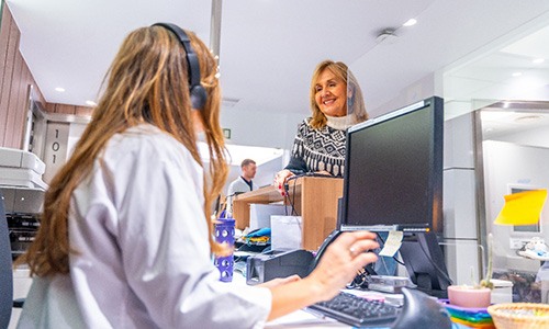 Smiling woman talking to dental receptionist 