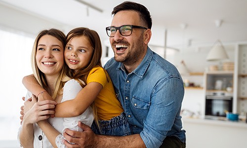 Family of three smiling at home 